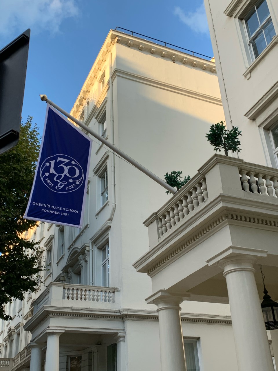 Queen's Gate School flag outside white building