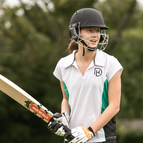 Girl holds cricket bat and smiles