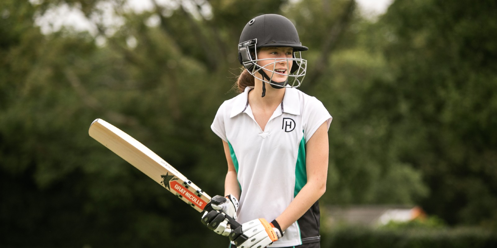 Girl in kit holding cricket bat ready to swing