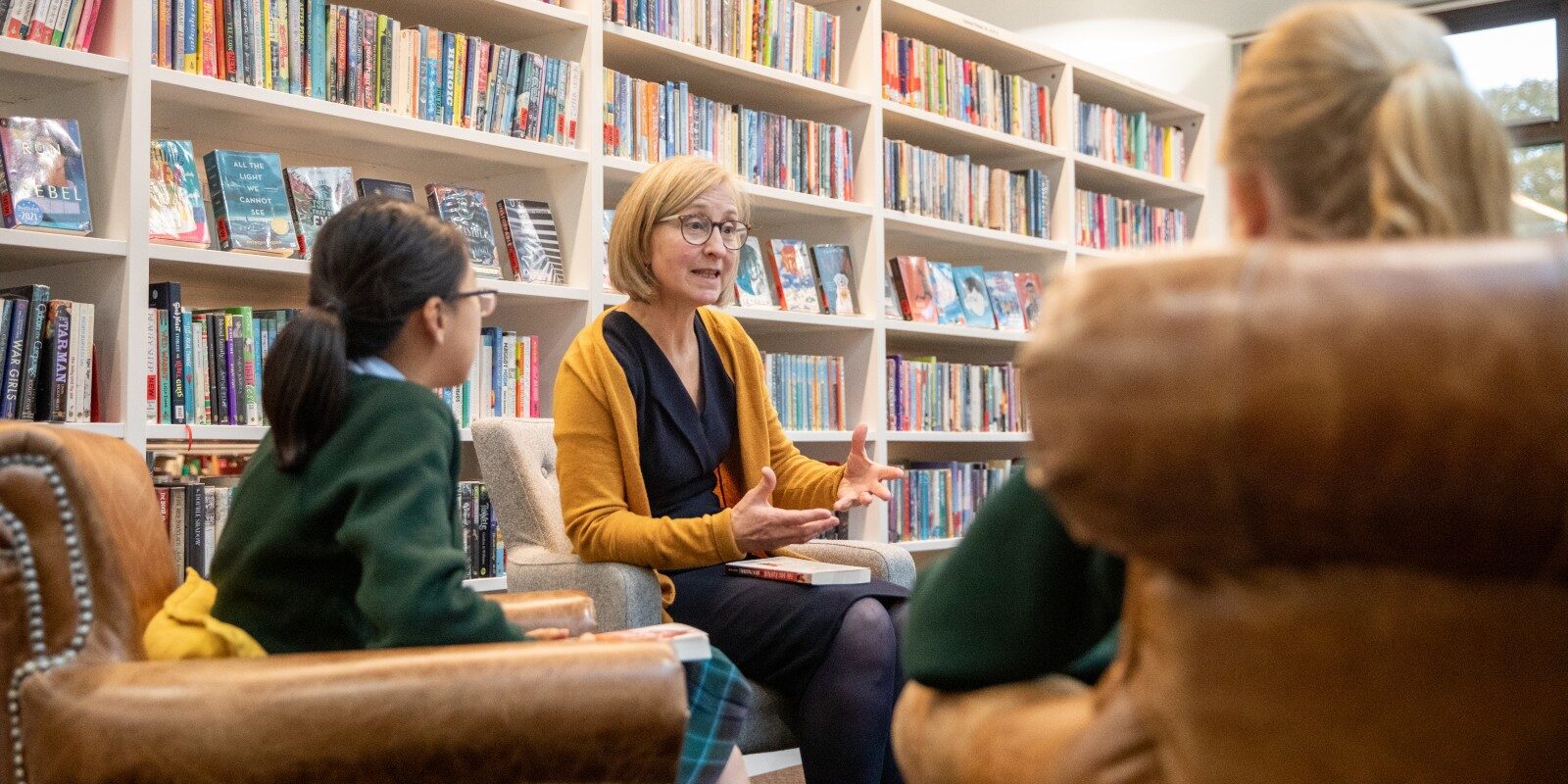 Librarian and pupils in a literature club discussing a book in the Library